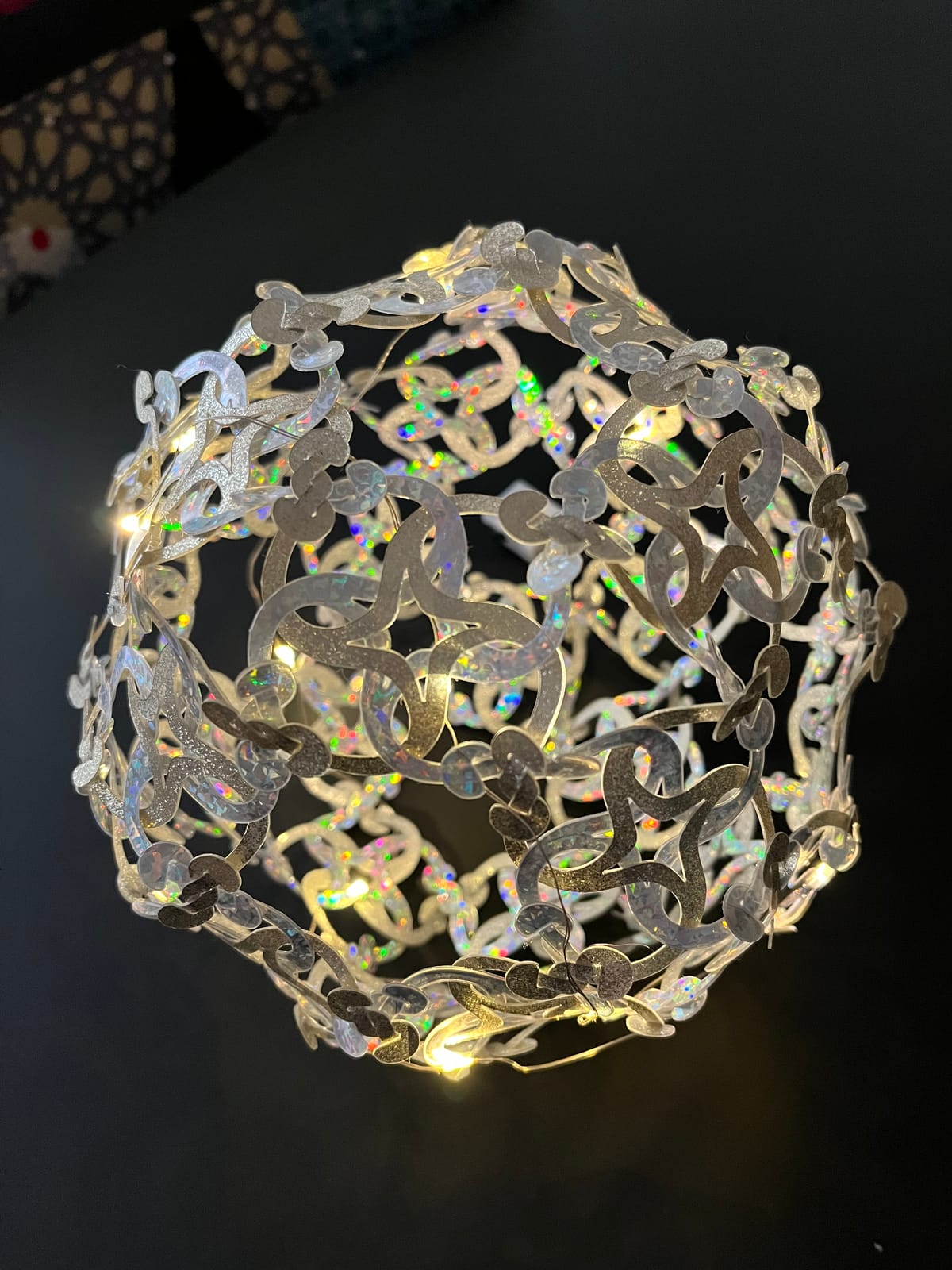 Boule en pièces argentées holographiques, allumée, sur fond noir