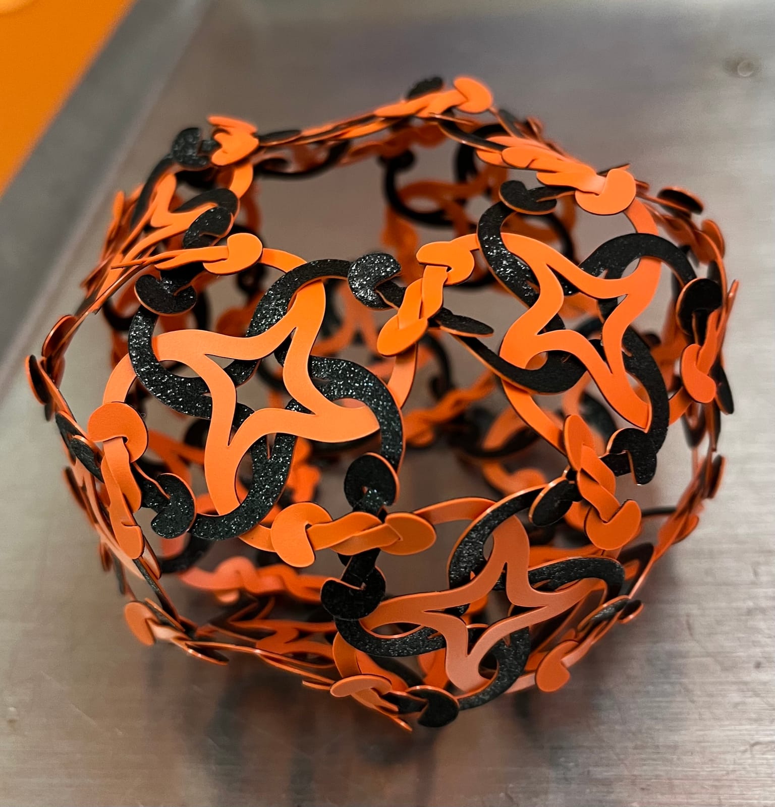 Boule ajourée en pièces orange et noires pailletées, construite pour Halloween